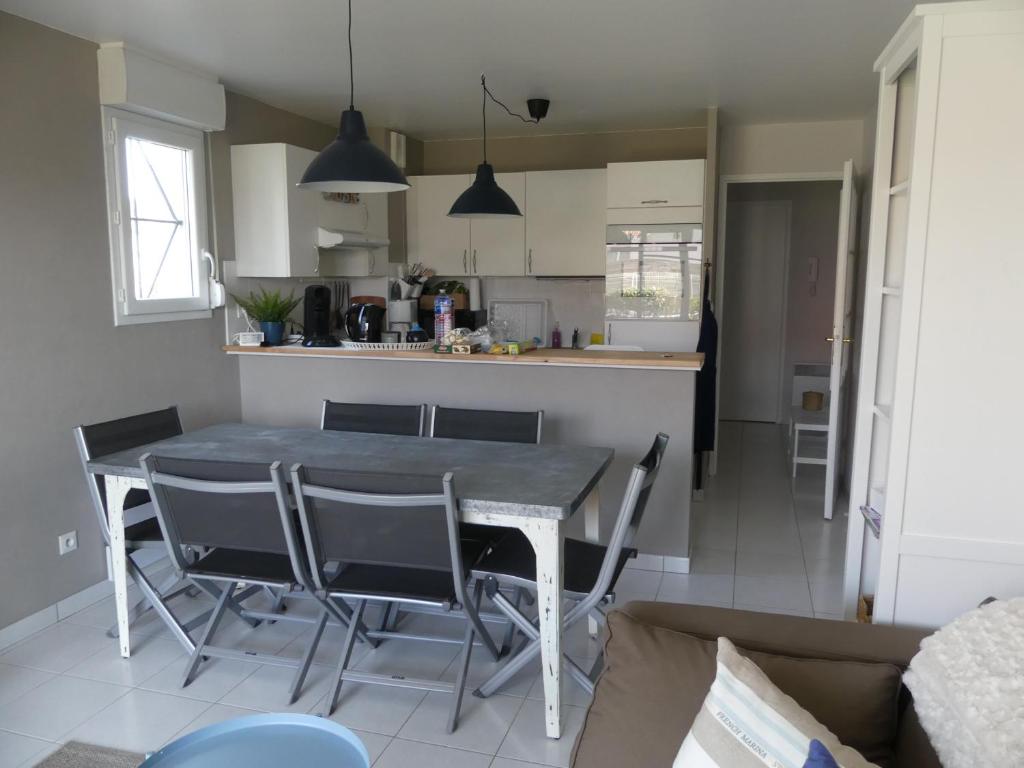 cocina y comedor con mesa y sillas en Au gré du vent, en Camiers