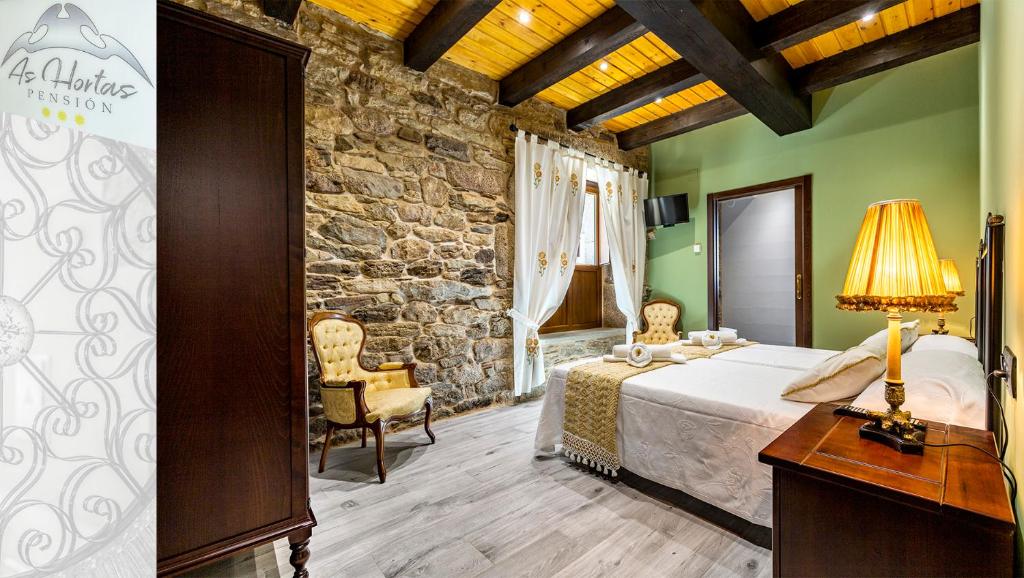 a bedroom with a bed and a stone wall at Pensión As Hortas in Palas de Rei