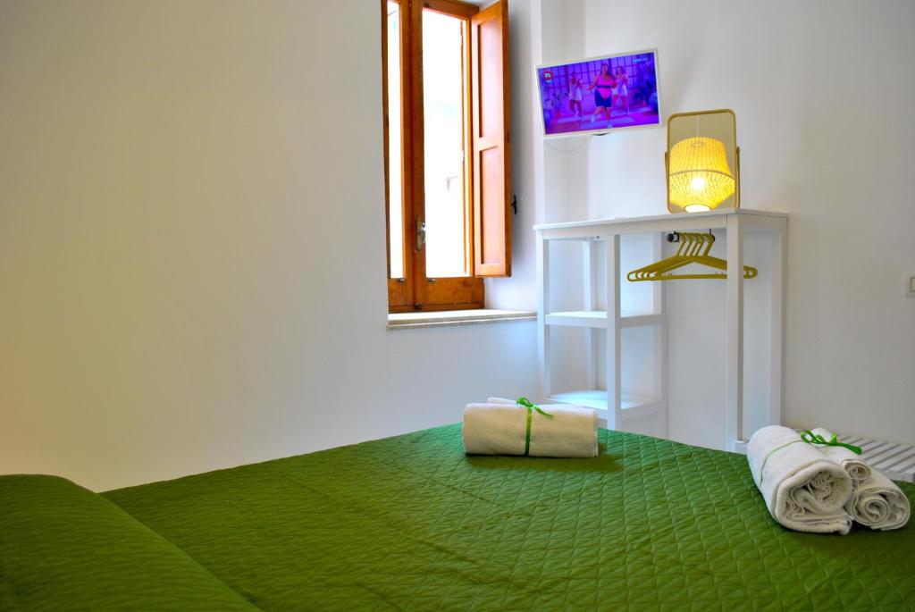 a room with a green bed with towels and a window at La casa di Nemi in Trapani