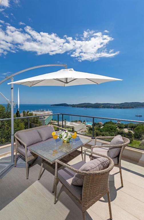 a patio with a table and chairs and an umbrella at Apartmani D & J with Heated Pool & Stunning Sea View in Orasac