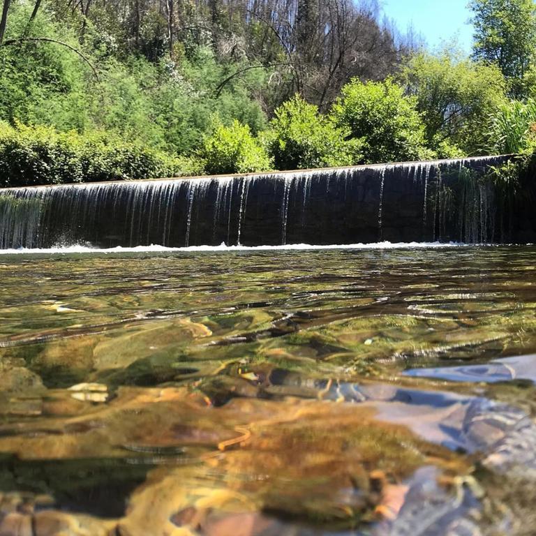 a river with a waterfall in the background at Casa do Moinho Novo in Fontão Fundeiro