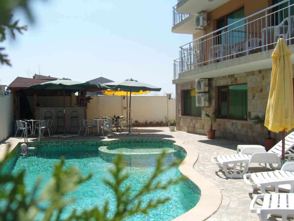 a swimming pool with chairs and umbrellas next to a building at Family Hotel Primo in Primorsko