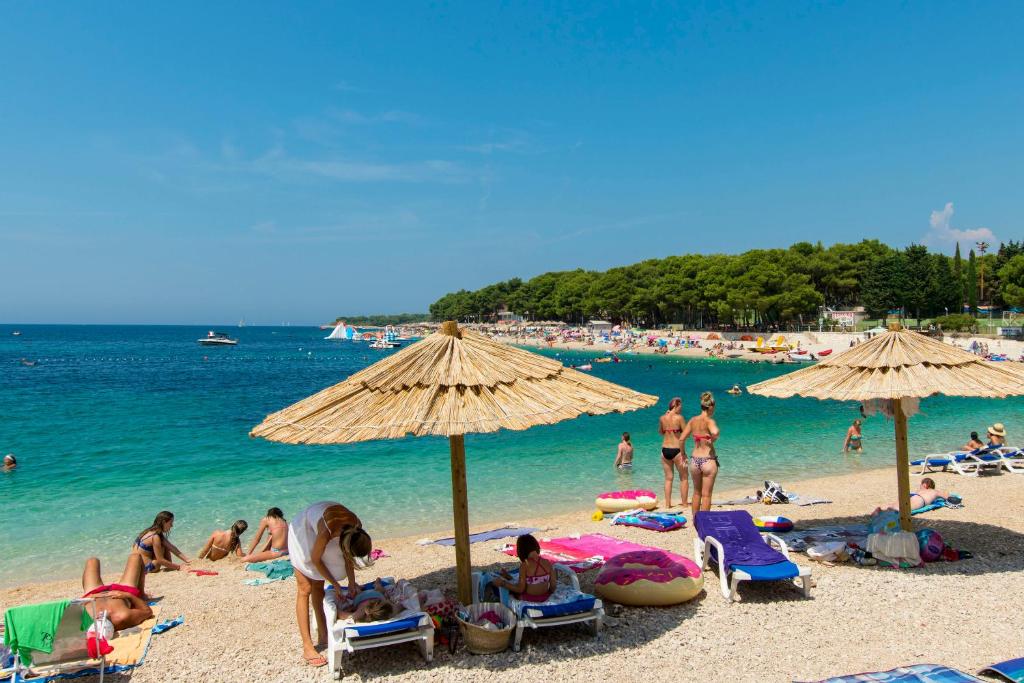 a group of people on a beach with umbrellas at Apartments and Rooms Jakov in Primošten