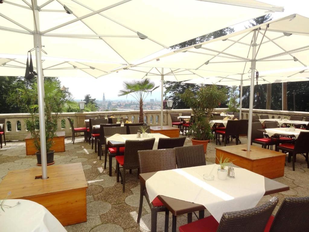 a restaurant with white umbrellas and tables and chairs at Hotel Restaurant Schweizerhaus in Klagenfurt