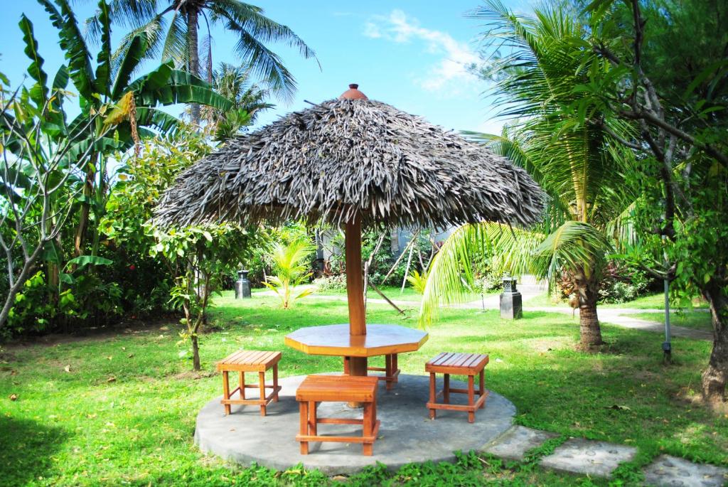 a table and four chairs under a straw umbrella at Tiara Homestay Pemuteran Bali in Pemuteran