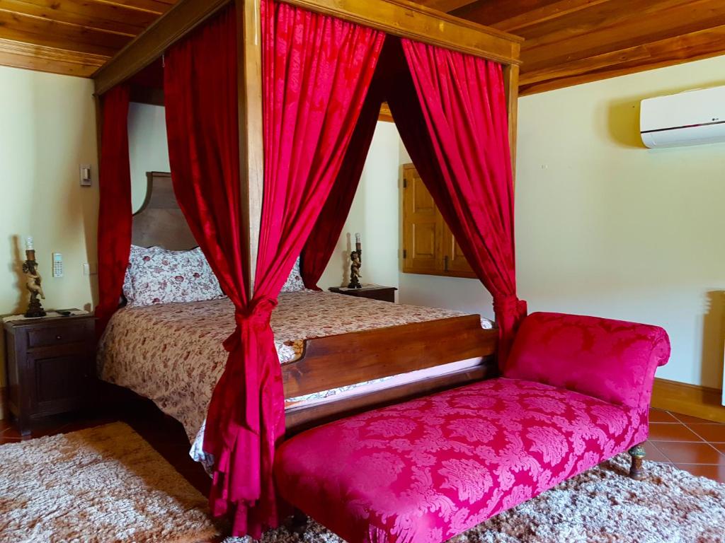 1 dormitorio con 1 cama con cortinas rojas y silla en Quinta Da Penela, en Vieira do Minho