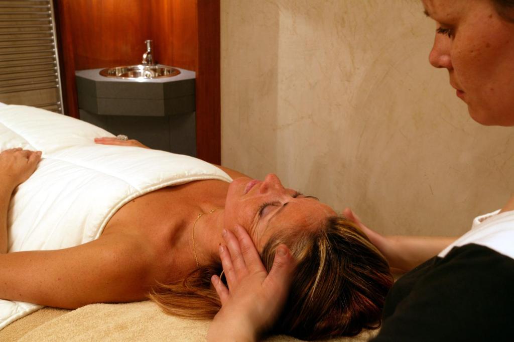 a woman laying on a bed looking at a woman at Le Hameau Albert 1er in Chamonix