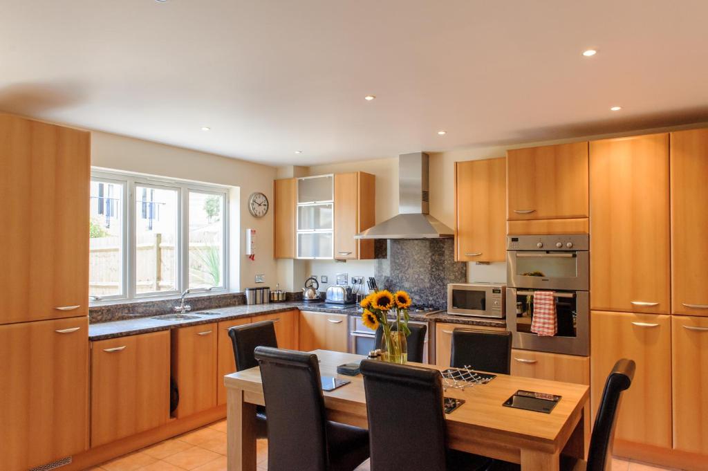 a kitchen with wooden cabinets and a wooden table at Camstay Townhouse in Cambridge