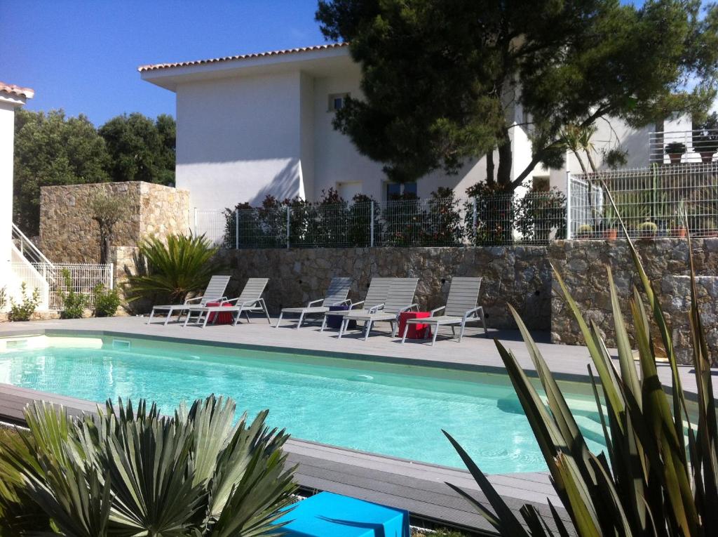 a swimming pool with chairs and a house at Résidence Le Clos Saint Paul in LʼÎle-Rousse