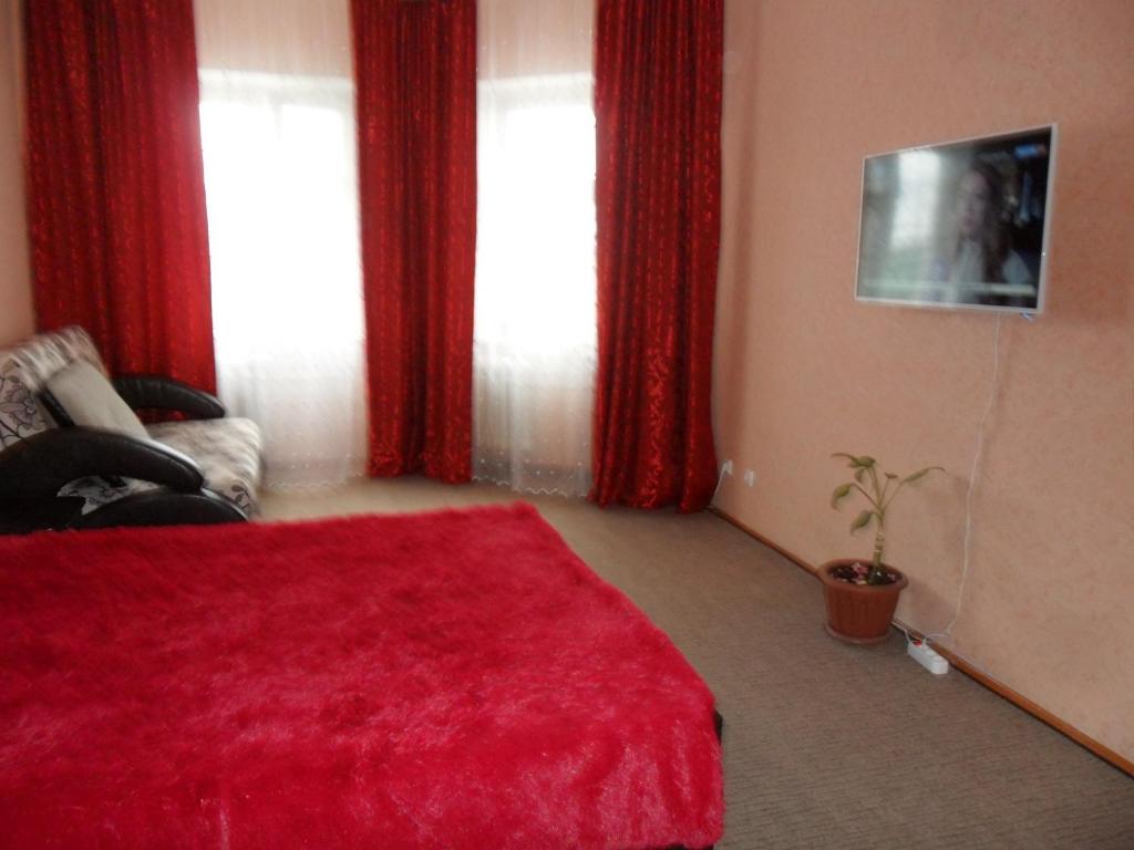 ニジネヴァルトフスクにあるApartment Internatsional'naya 2/1のベッドルーム1室(赤いカーテン、赤い毛布付きのベッド1台付)