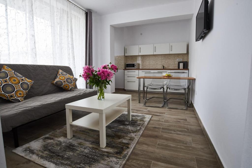 uma sala de estar com um sofá e uma mesa com flores em AT Central Apartments em Bucareste
