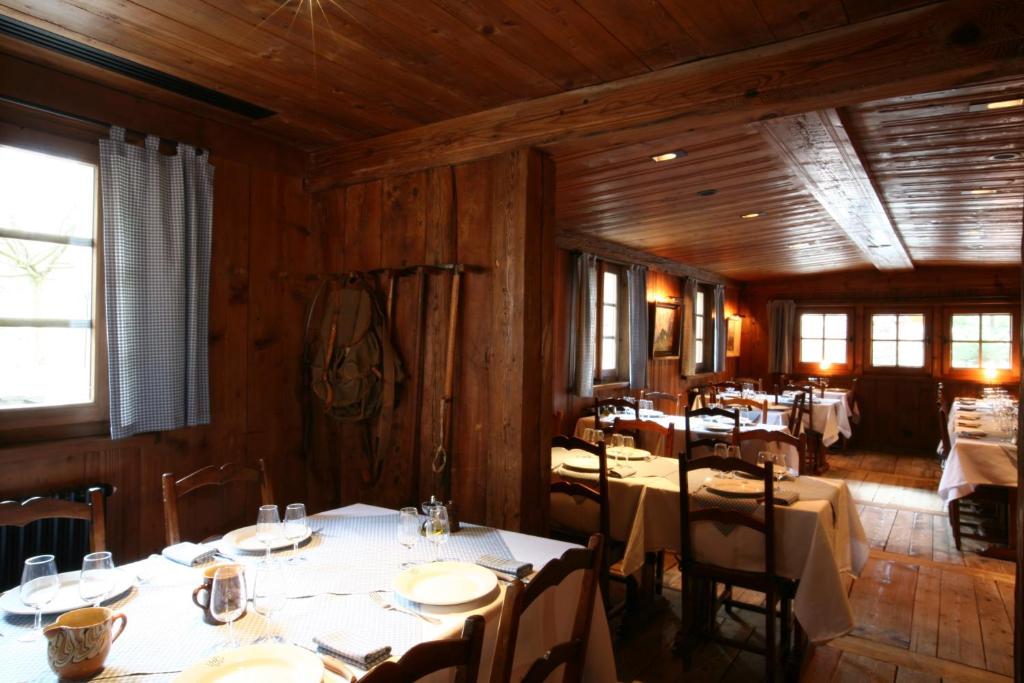 a dining room with tables and chairs and wooden walls at Le Hameau Albert 1er in Chamonix