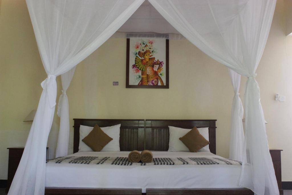 a bedroom with a canopy bed with a teddy bear on it at Bali Gecko Homestay in Pemuteran