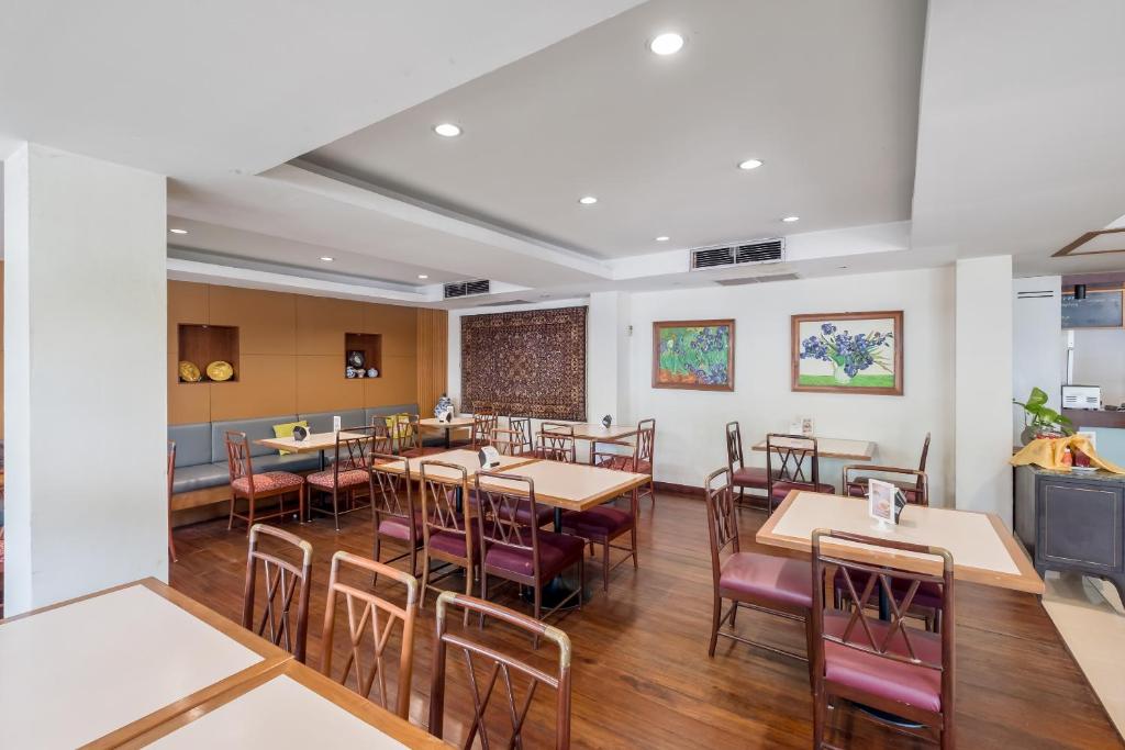 A bright dining room is set with wooden tables and mixed chairs.