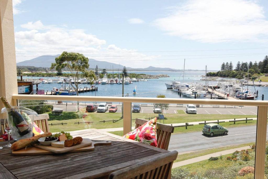 a table on a balcony with a view of a marina at Vista Marina Penthouse #5 - Amazing views & location in Bermagui