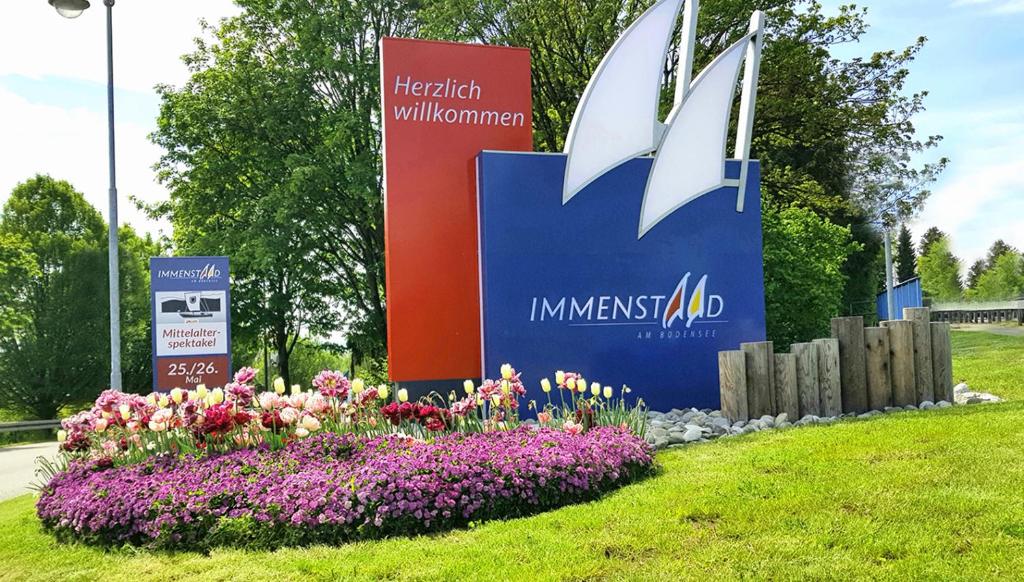 a sign for an imex ad in a park with flowers at Fewo Saur in Immenstaad am Bodensee