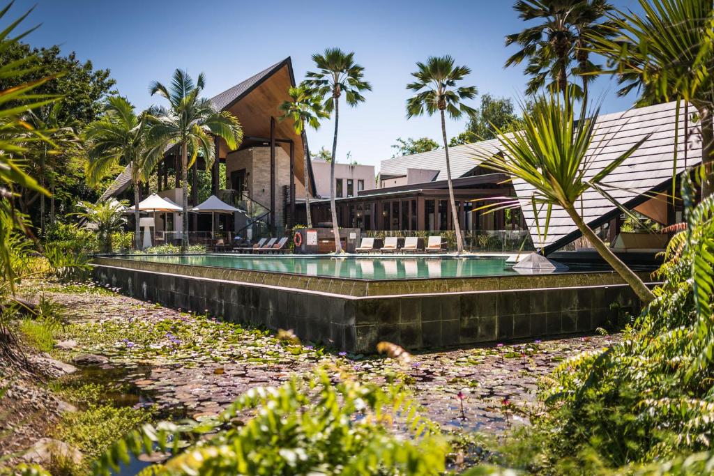 un complexe avec une piscine et des palmiers dans l'établissement Niramaya Villas and Spa, à Port Douglas