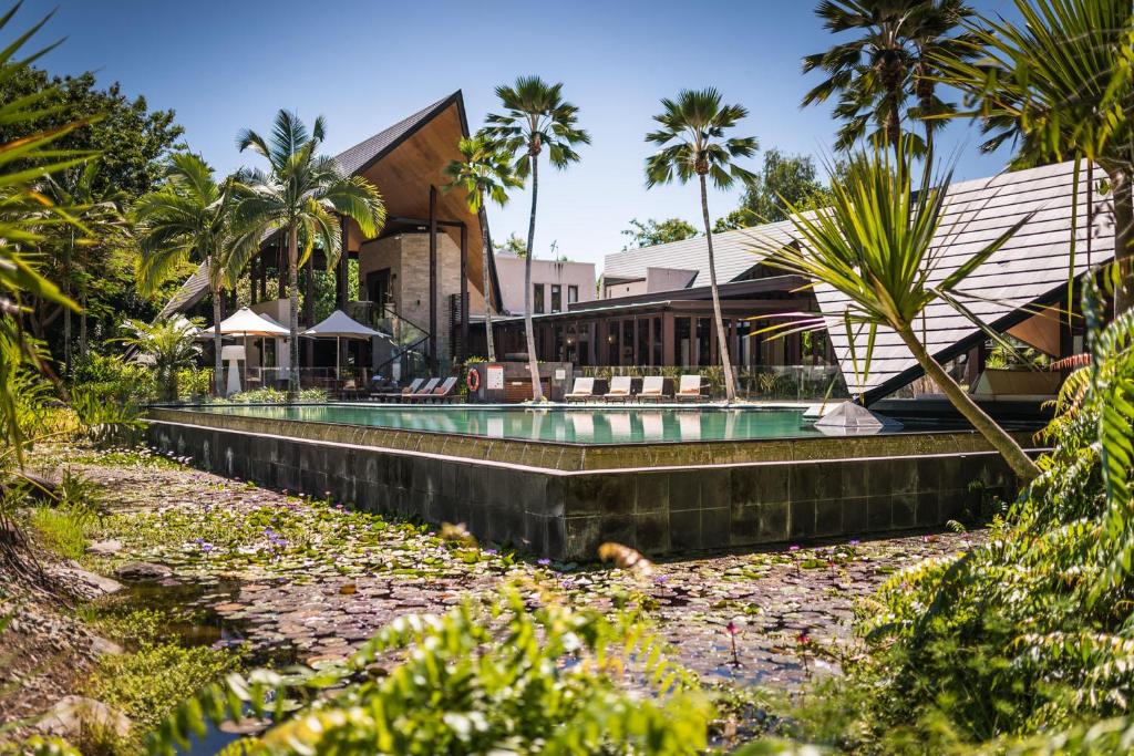 a resort with a swimming pool and palm trees at Niramaya Villas and Spa in Port Douglas