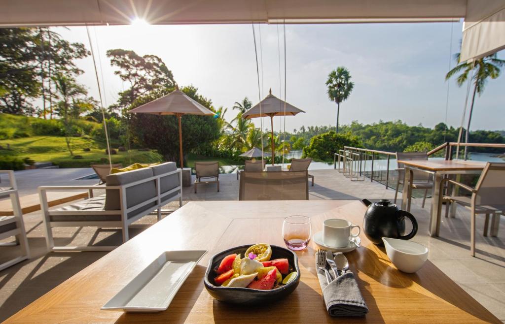 a table with a bowl of fruit and a glass of wine at Tri by Amaya in Ahangama