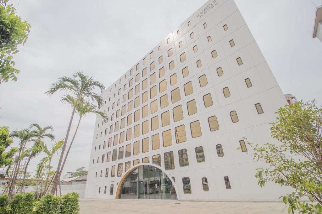 duży biały budynek z palmą w obiekcie Justice Hotel w mieście Bangkok
