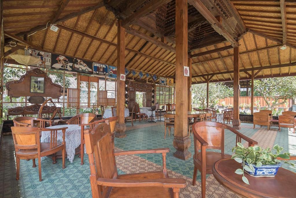 a restaurant with wooden tables and chairs and tables and chairs at RedDoorz @ Maribaya Street 2 in Bandung