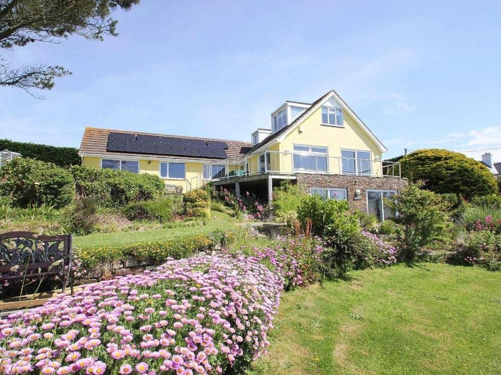a large yellow house with a garden of flowers at Windrush in Newquay