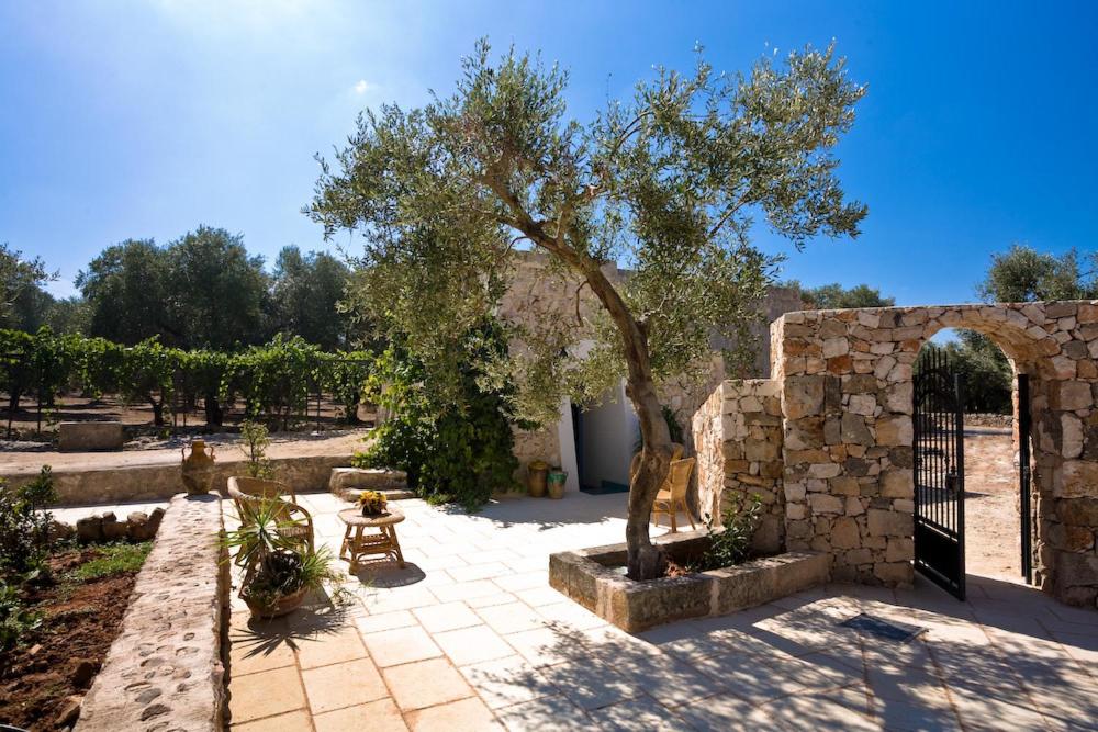 un patio con un árbol y una pared de piedra en Tenuta De Marco, en Presicce