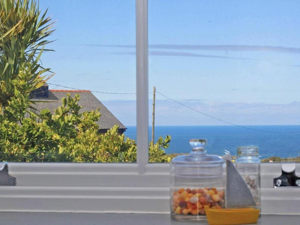 - une vue sur l'océan depuis une fenêtre avec des pots de fruits dans l'établissement Bal View, à Lower Boscaswell