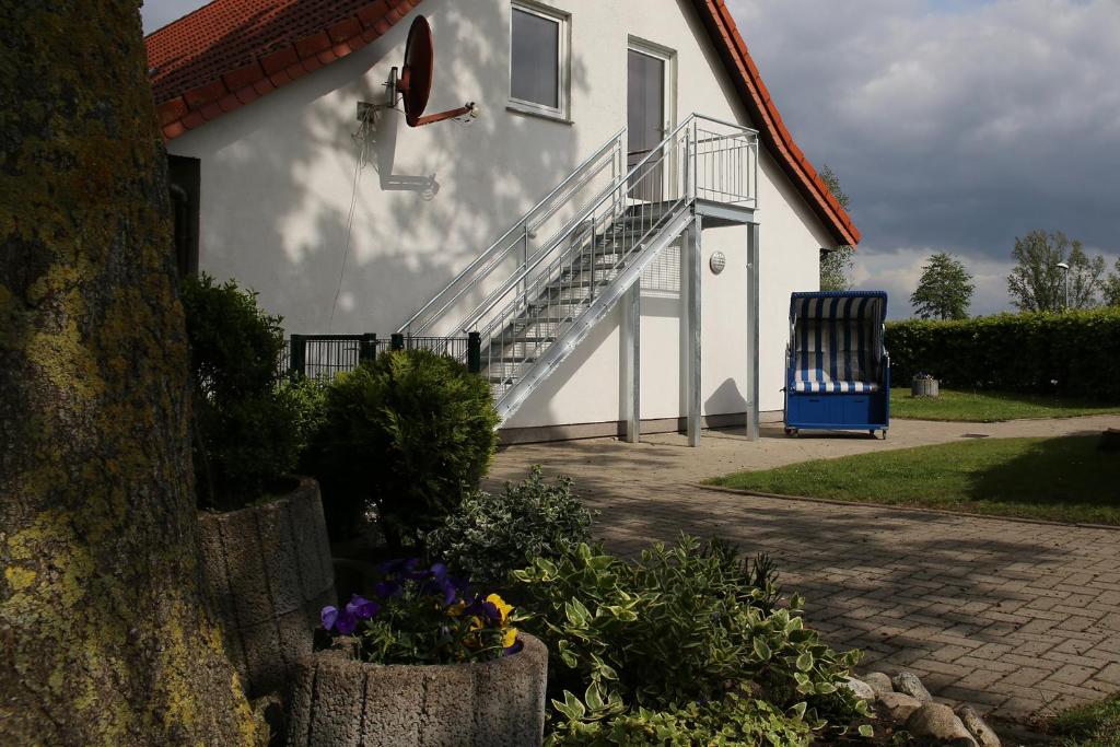 una casa bianca con scala e sedia blu di Ferienwohnung am Schwarzen Wehl a Dorum-Neufeld
