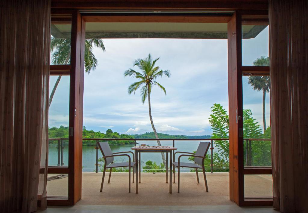a table and chairs on a balcony with a view of the water at Tri by Amaya in Ahangama