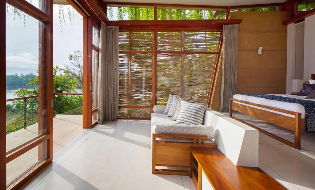 a bedroom with a bed and a large window at Tri by Amaya in Ahangama