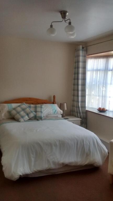 a bedroom with a white bed and a window at Lewinsdale Lodge in Weston-super-Mare