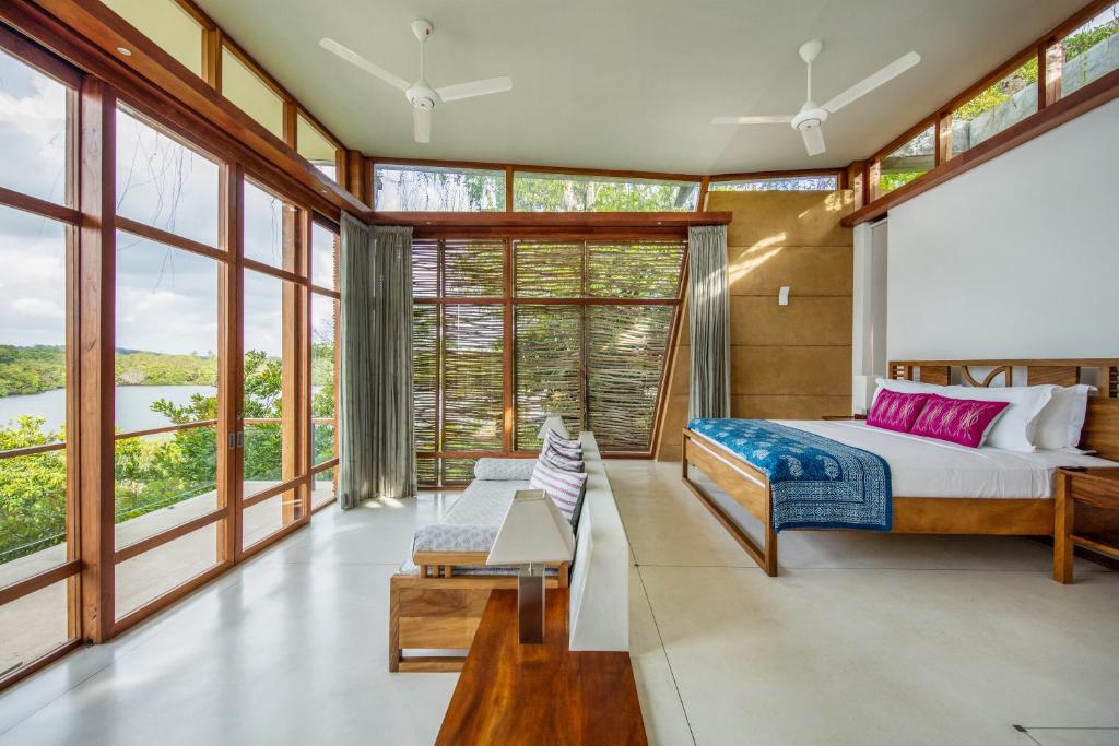 a bedroom with a king sized bed and large windows at Tri by Amaya in Ahangama