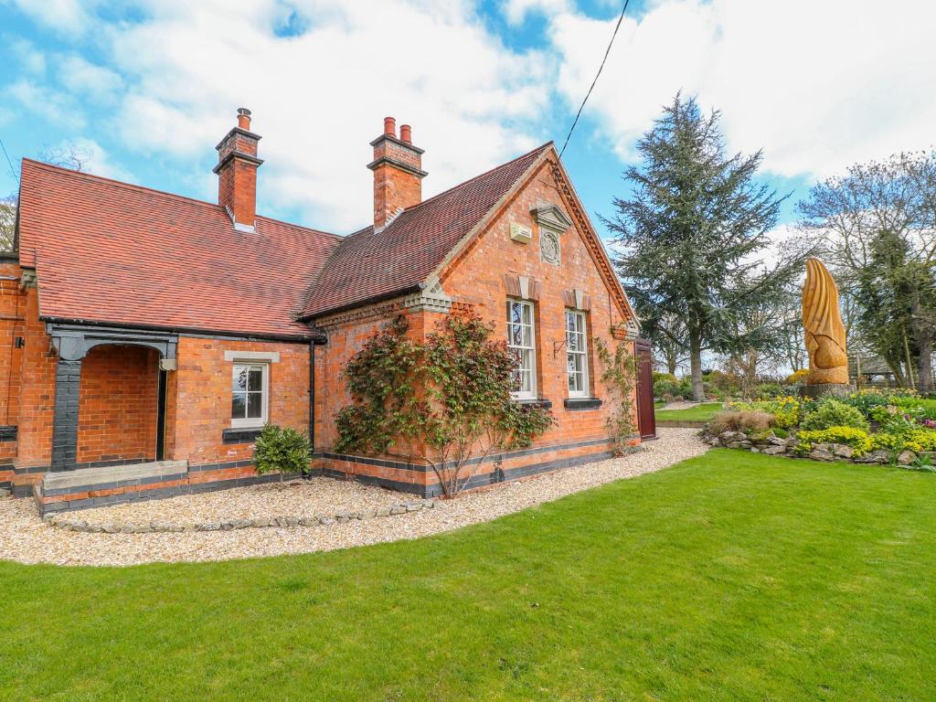 an old brick house with a green yard at South Lodge - Longford Hall Farm Holiday Cottages in Ashbourne