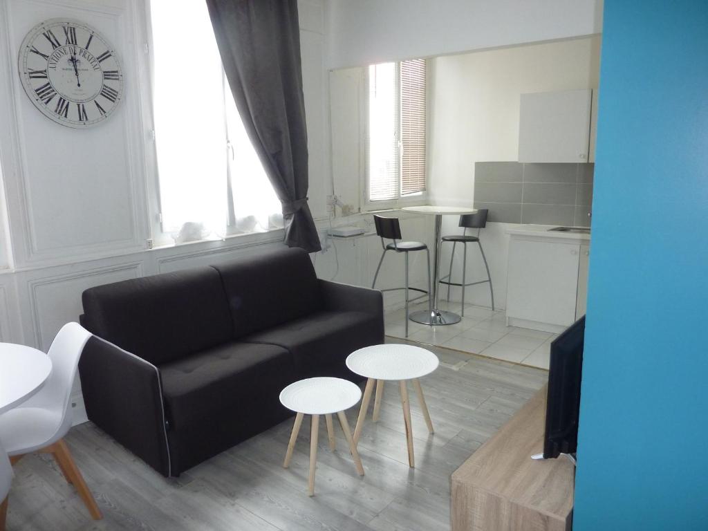 a living room with a couch and tables and a clock at Le grand cauchois in Rouen