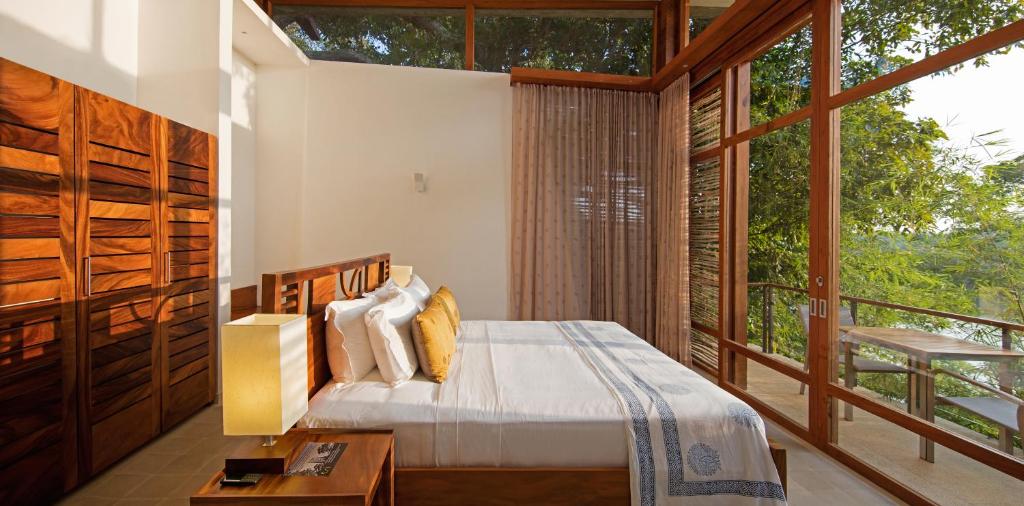 a bedroom with a bed and a large window at Tri by Amaya in Ahangama
