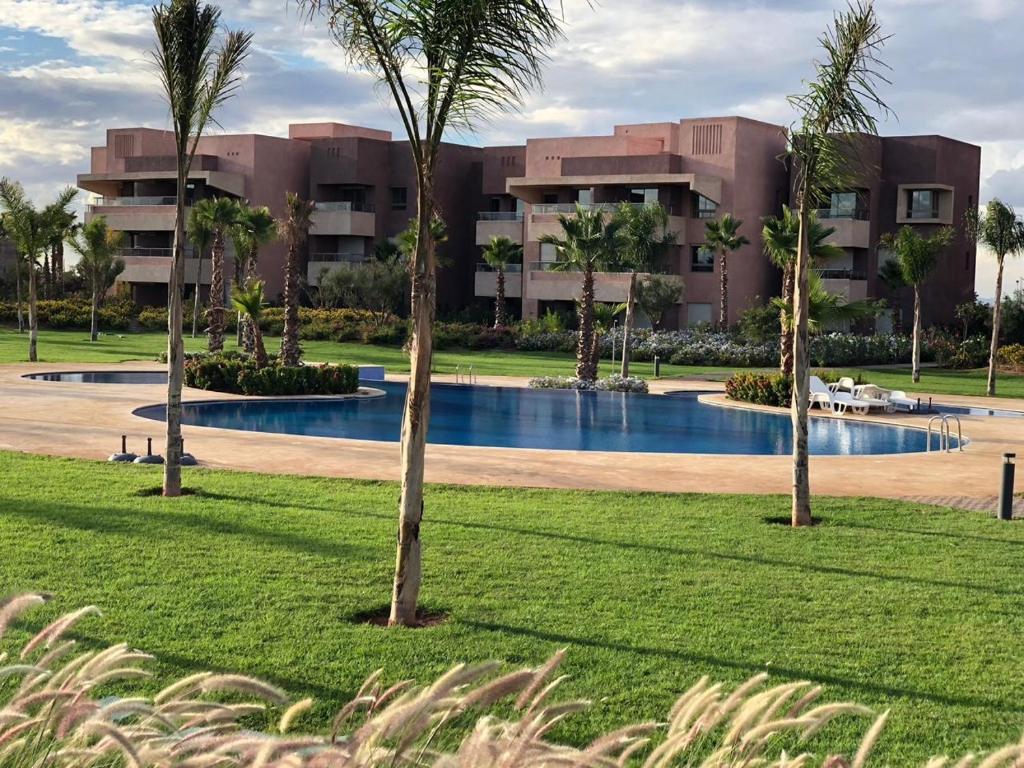 a resort with a swimming pool and palm trees at bel appartement F2 au golf de Montgomery in Marrakesh