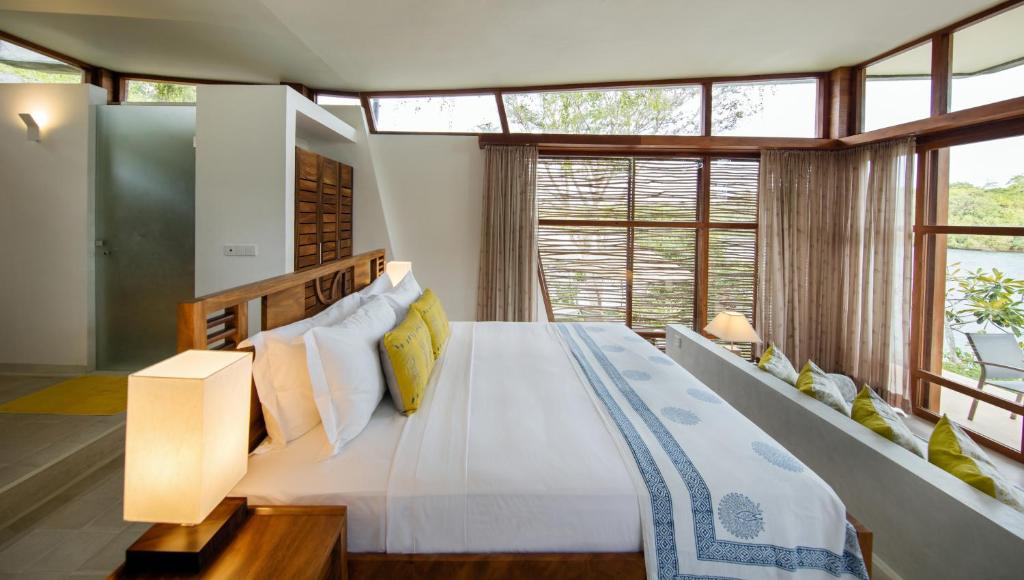 a bedroom with a large white bed and windows at Tri by Amaya in Ahangama