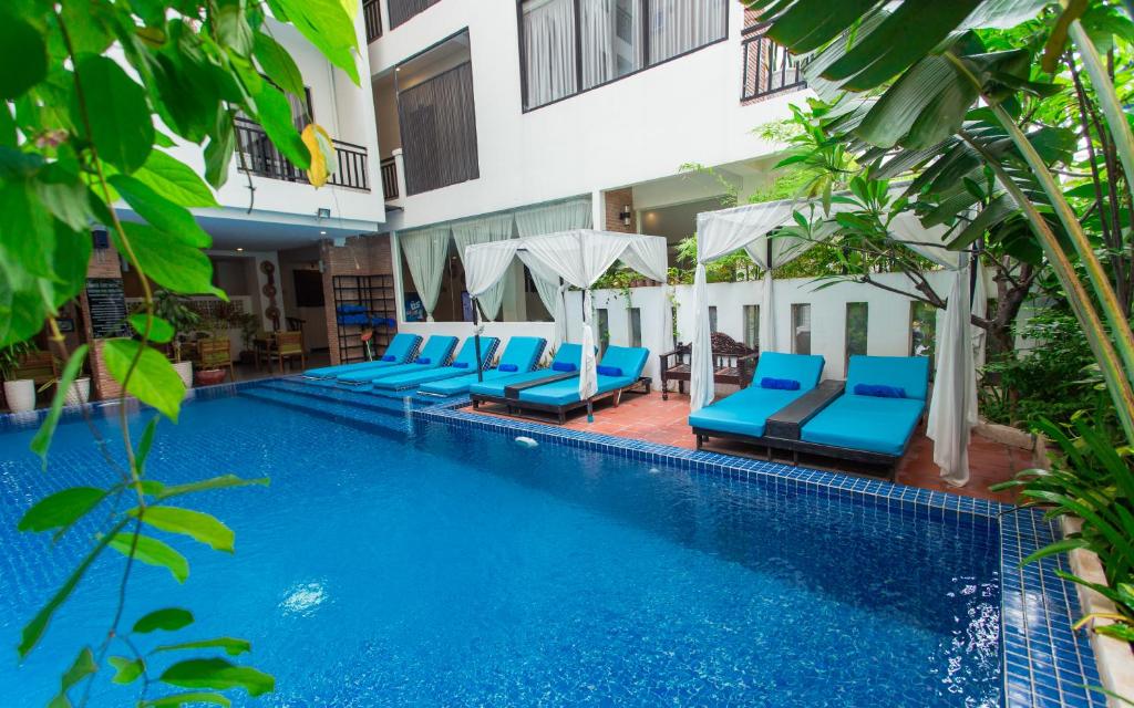 a swimming pool with blue chairs and a building at Home Chic Hotel in Phnom Penh
