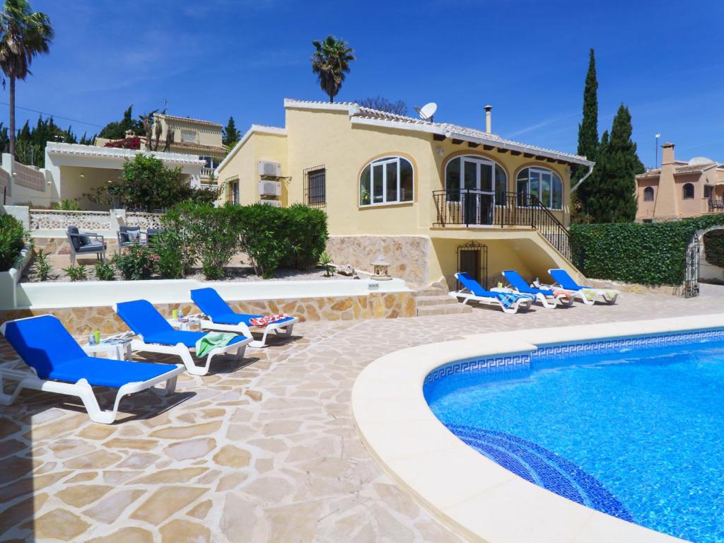 a villa with a swimming pool and blue lounge chairs at Holiday Home Grevol by Interhome in Balcon del Mar