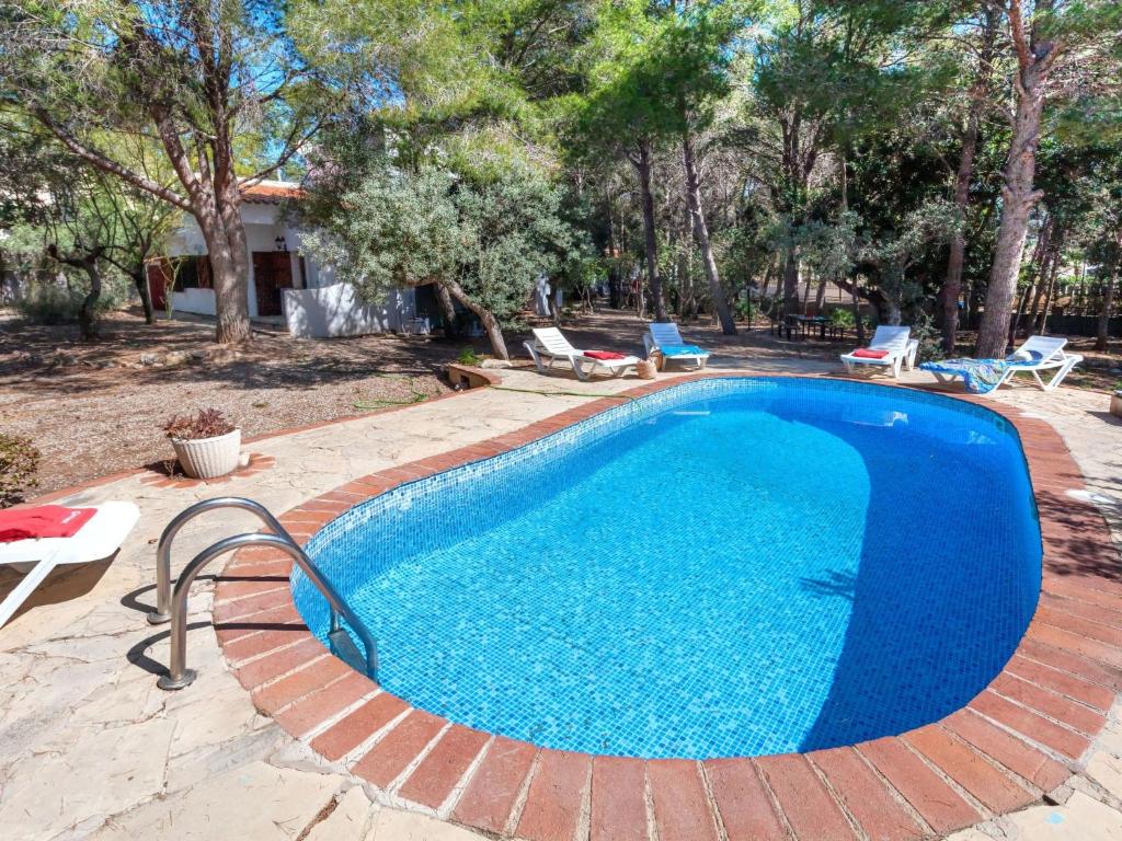 a large swimming pool with a brick patio and trees at Villa Villa Pinos by Interhome in Les tres Cales