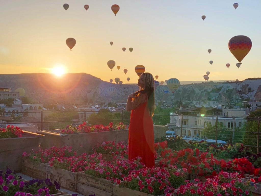 Una donna con un vestito rosso che guarda le mongolfiere di Design Cave Hotel a Göreme