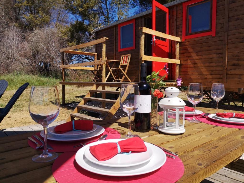 a wooden table with plates and glasses of wine at Moledos glamping in Aljezur