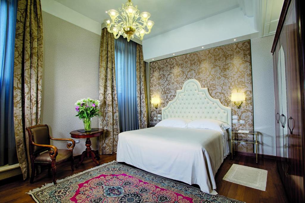 a bedroom with a white bed and a chandelier at Hotel Santa Chiara in Venice