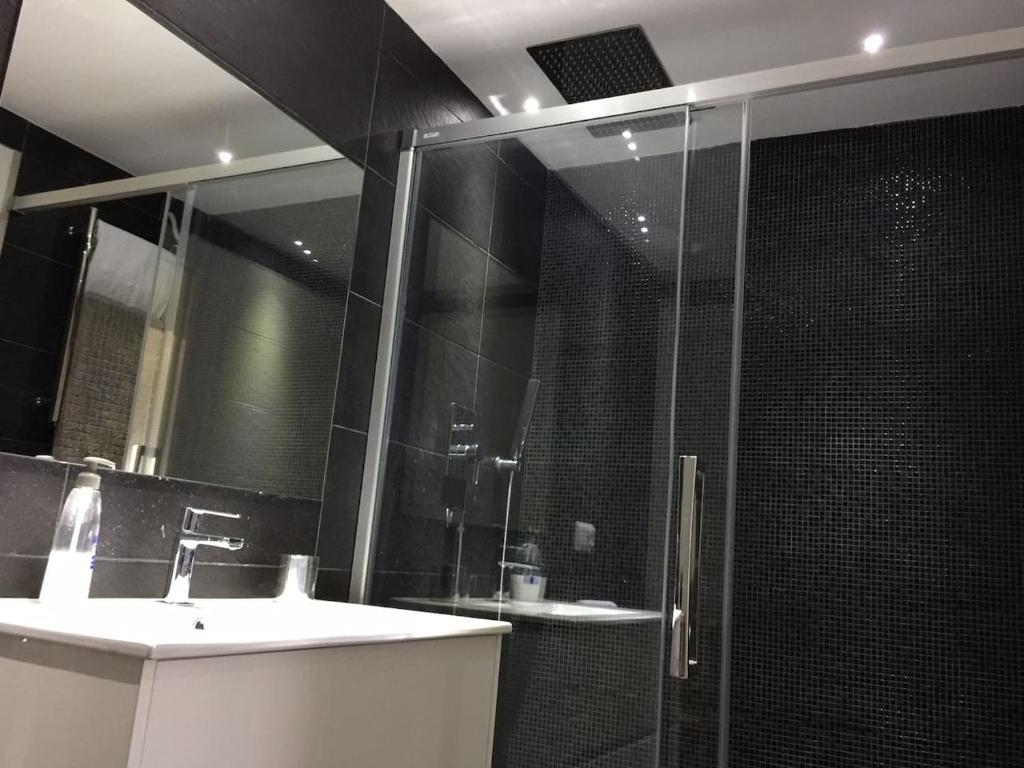 ein Bad mit einer Dusche, einem Waschbecken und einem Spiegel in der Unterkunft Piso cerca del Toralin y La Rosaleda in Ponferrada