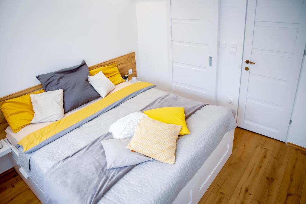 ein Bett mit gelben und grauen Kissen darauf in der Unterkunft Cozy apartment in the downtown in Győr