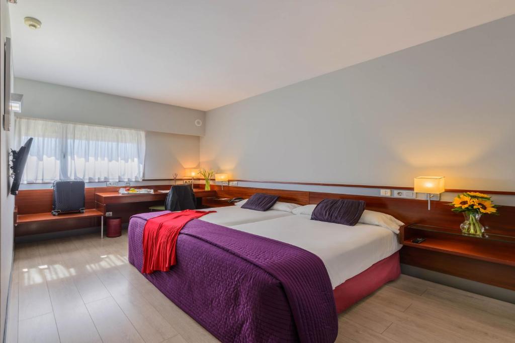 a bedroom with a large bed and a living room at Hostal Porcel Torrejón in Torrejón de Ardoz
