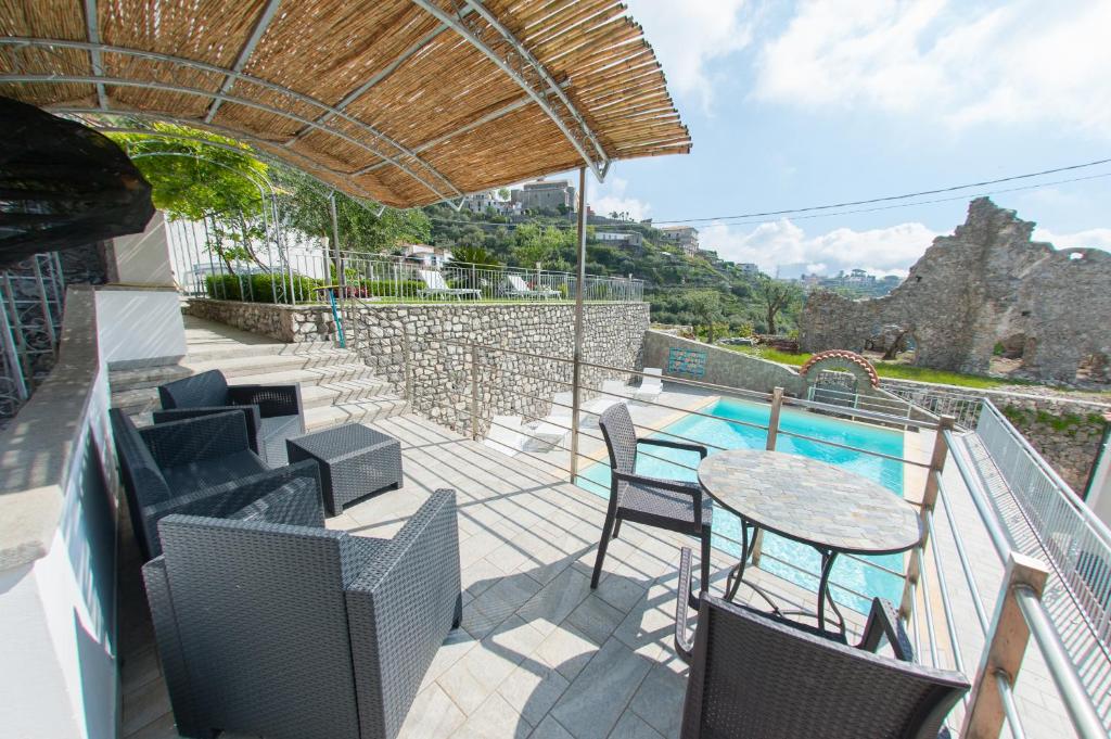 un patio con tavolo, sedie e piscina di Lo Smeraldo Luxury Home Ravello by ElodeaGroup a Scala