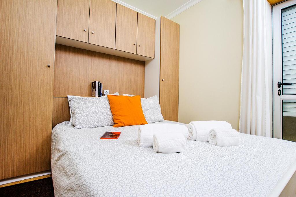 um quarto com uma grande cama branca e uma almofada laranja em Heart of Aveiro Apartment em Aveiro