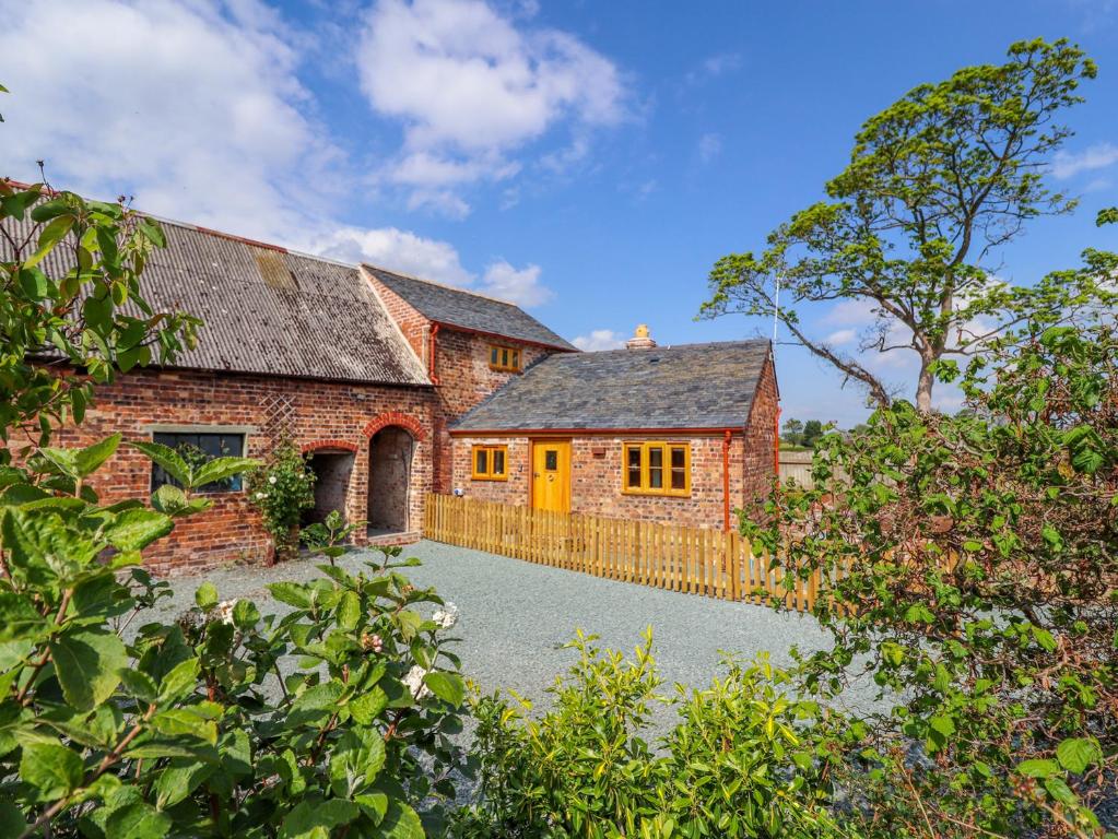 an old brick house with a yellow door at The Tractor Shed in Oswestry